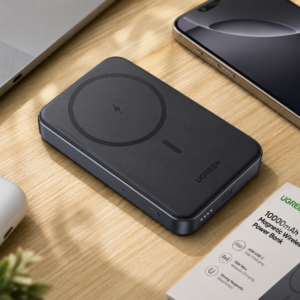 UGREEN 10000mAh Magnetic Wireless Power Bank Space Gray placed on a modern workspace desk beside a laptop, smartphone, and earbuds case.